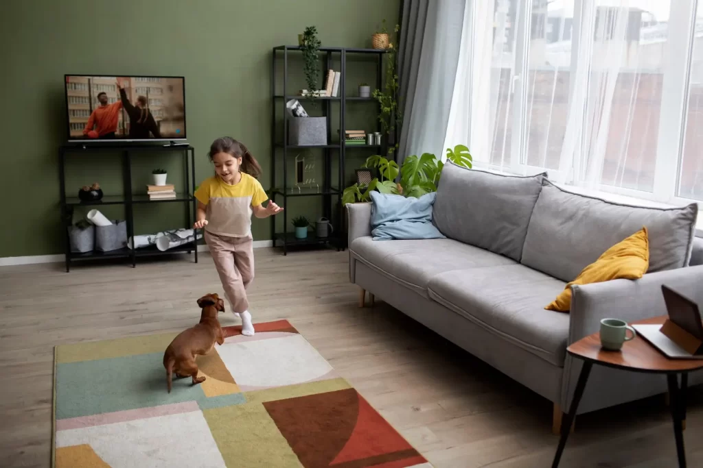 A child and a dog are playing on a carpet