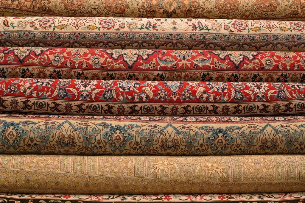Several Iranian carpets rolled up and placed side by side